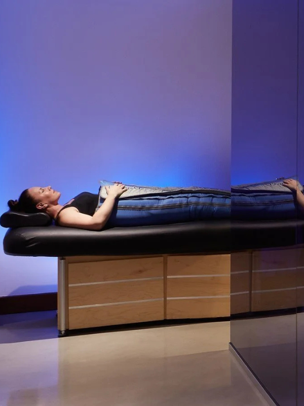 Person reclining during a Ballancer Pro compression therapy session using specialized compression garments.